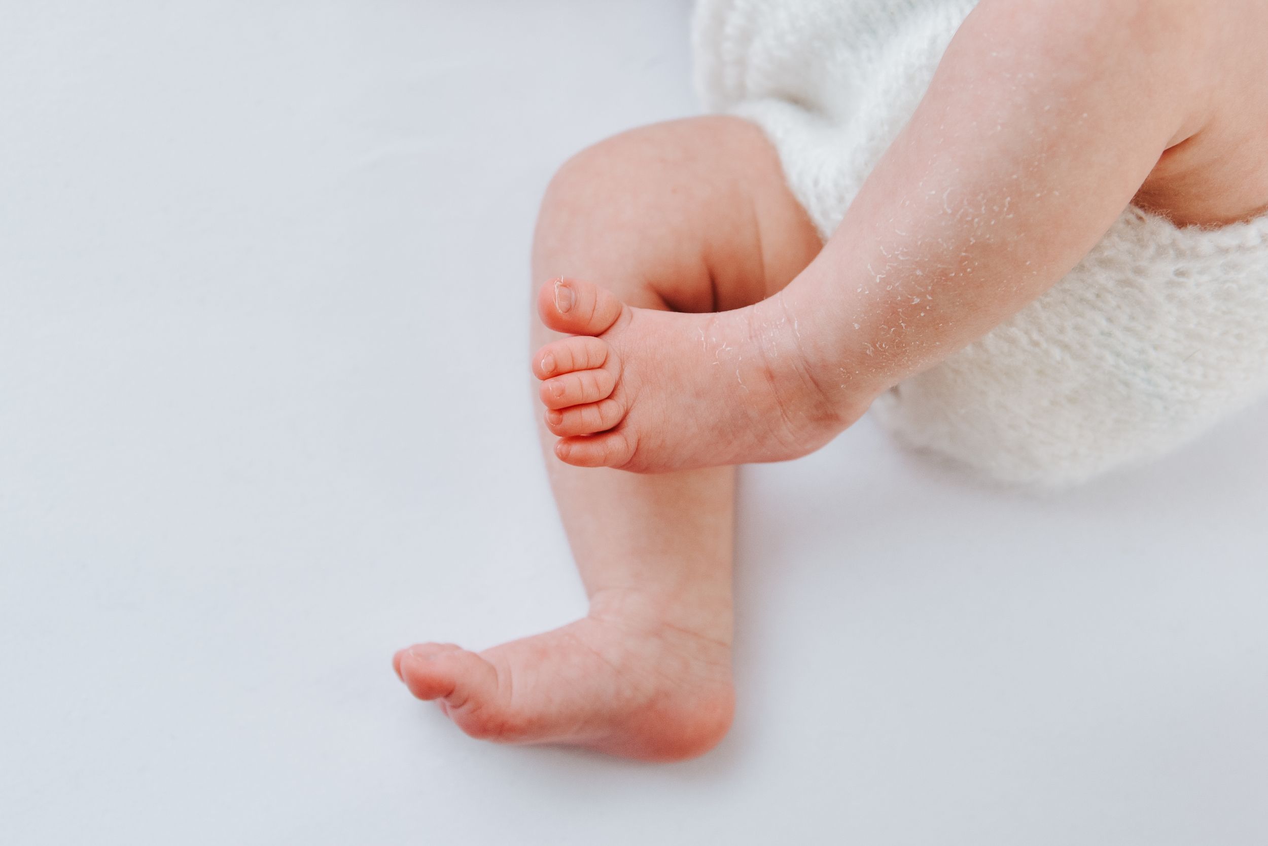 Close up of tiny baby toes and feet against white background.