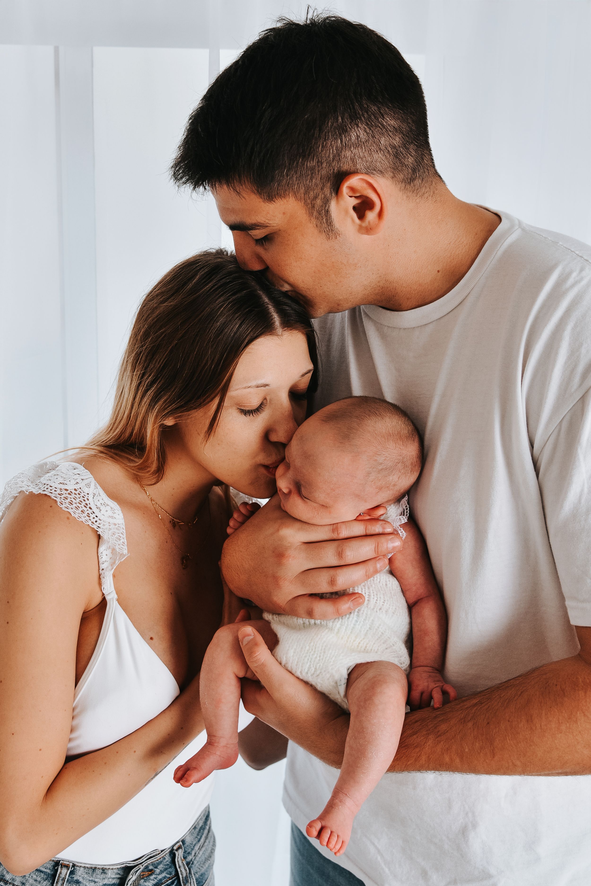 Intimate family portrait in soft white tones.