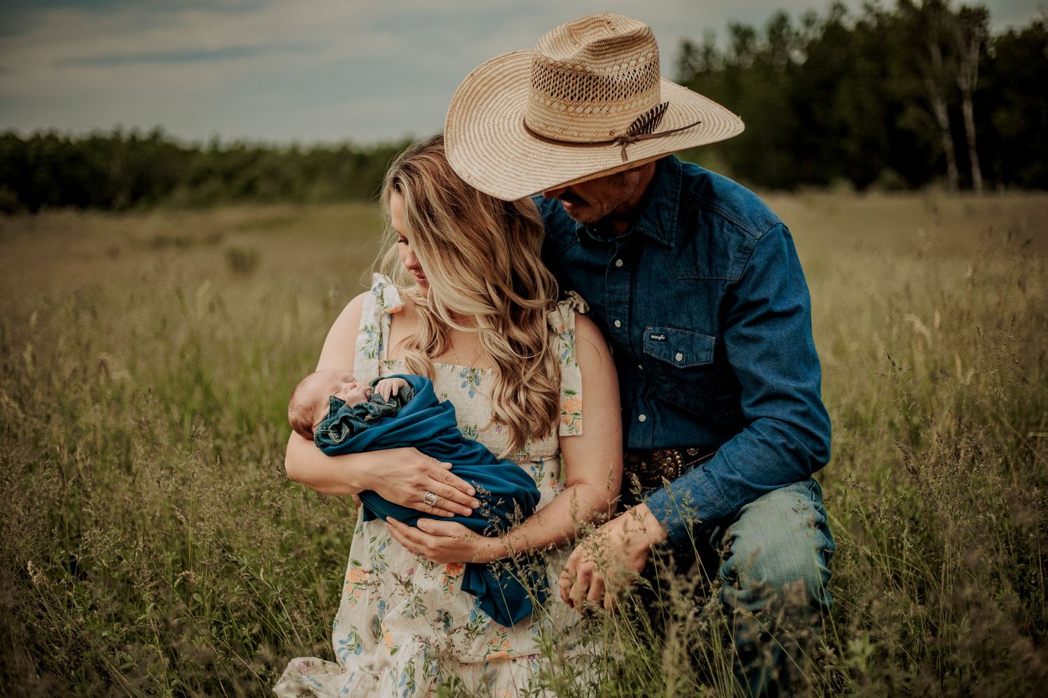 Black cowboy hat and turquoise denim jacket lying on grass with orange sunflowers at sunset.