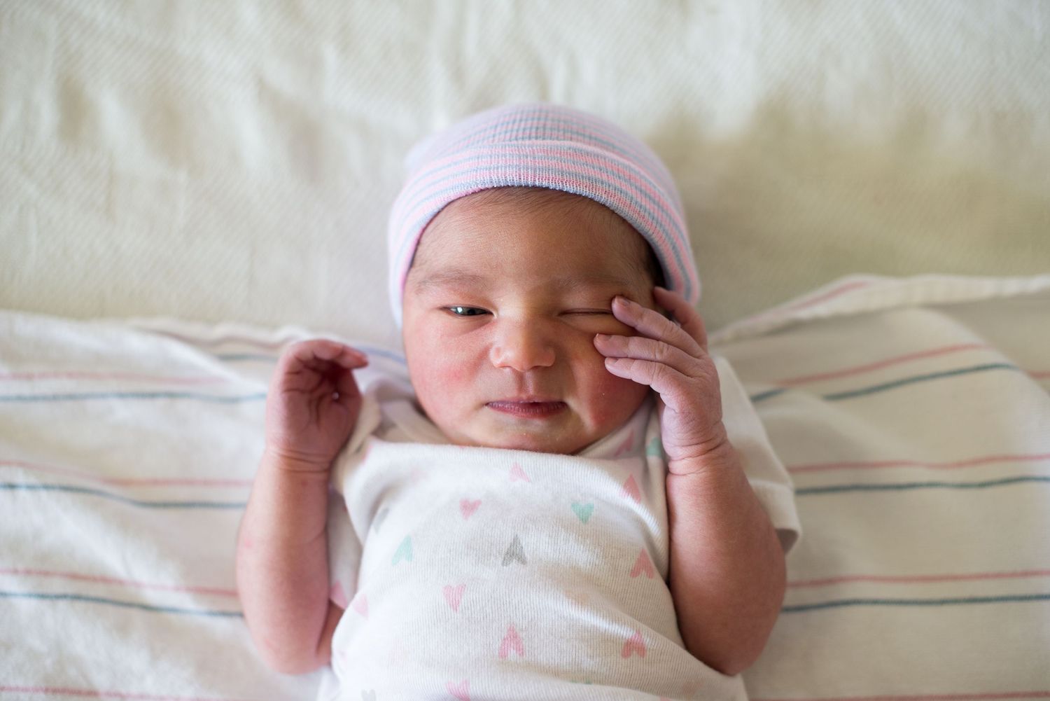 A newborn lies in a clear plastic hospital bassinet with medical information card visible above. Fresno Fresh 48 Hospital Photographer