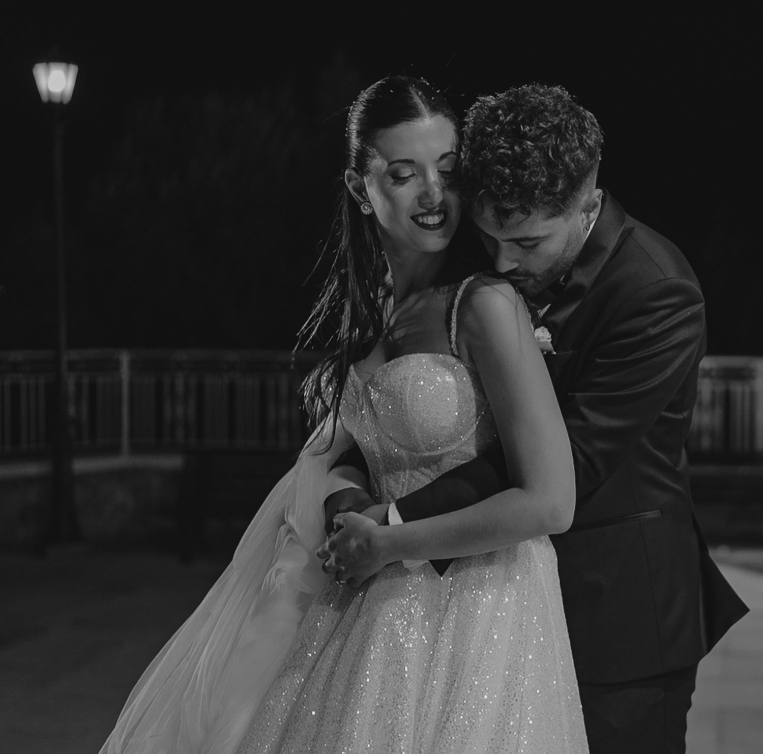 Black and white wedding photo of couple sharing an intimate embrace during their nighttime outdoor celebration.