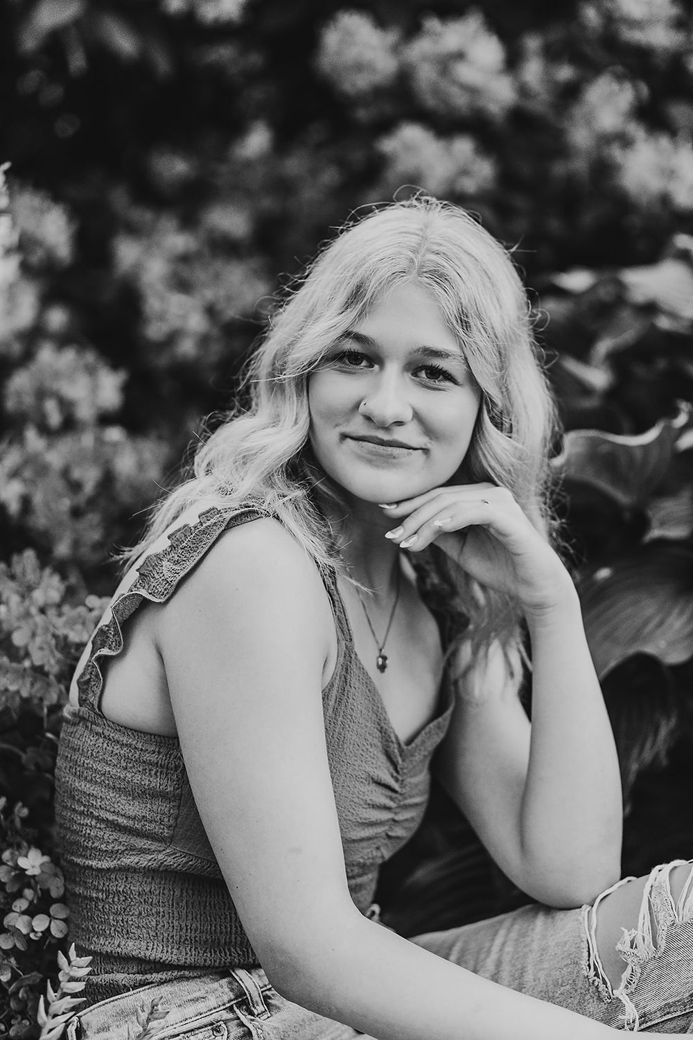 Black and white outdoor portrait showing relaxed casual style amidst natural garden setting.