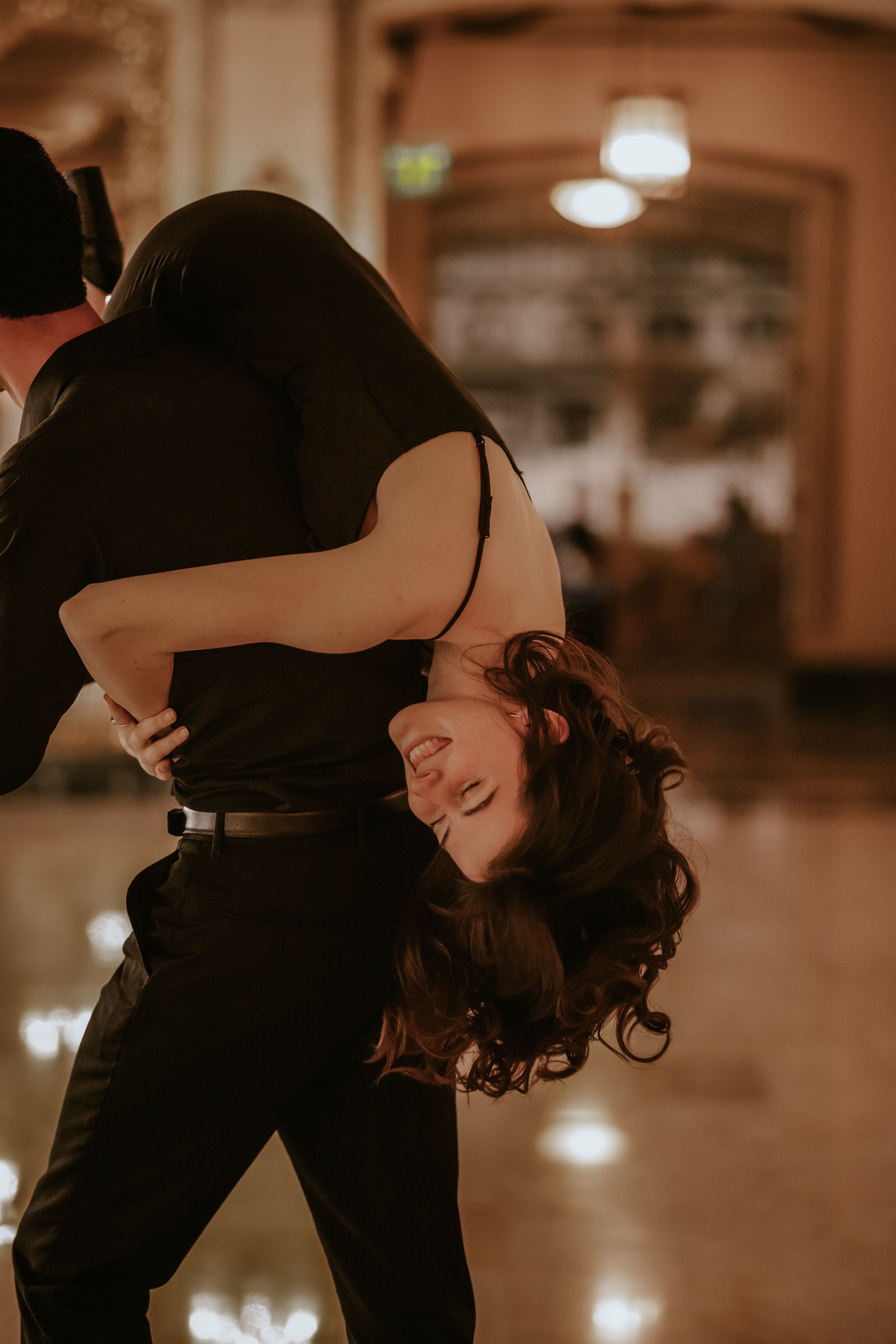A couple dancing together in an intimate embrace under dim lighting, creating a romantic silhouette effect.