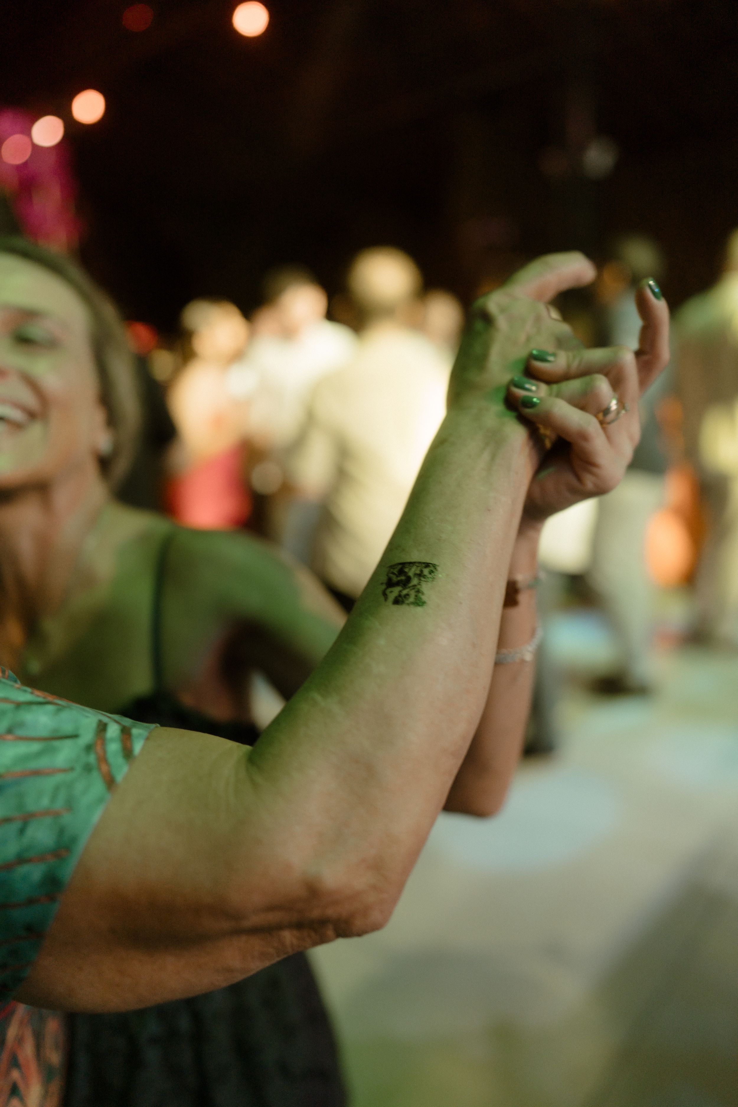 Party guests dancing and celebrating with colorful lighting and festive mood at a nighttime event.