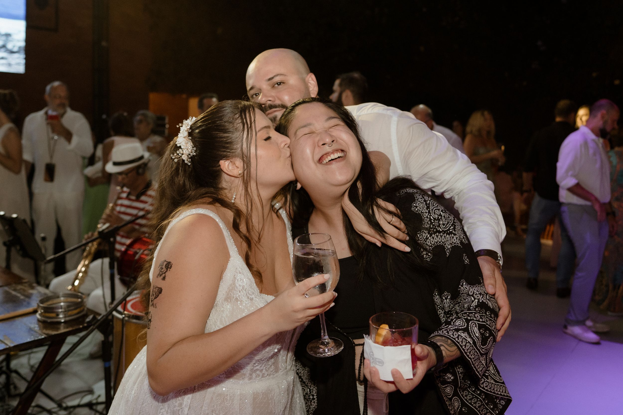 Wedding guests sharing joyful moments together while holding drinks at an evening reception.