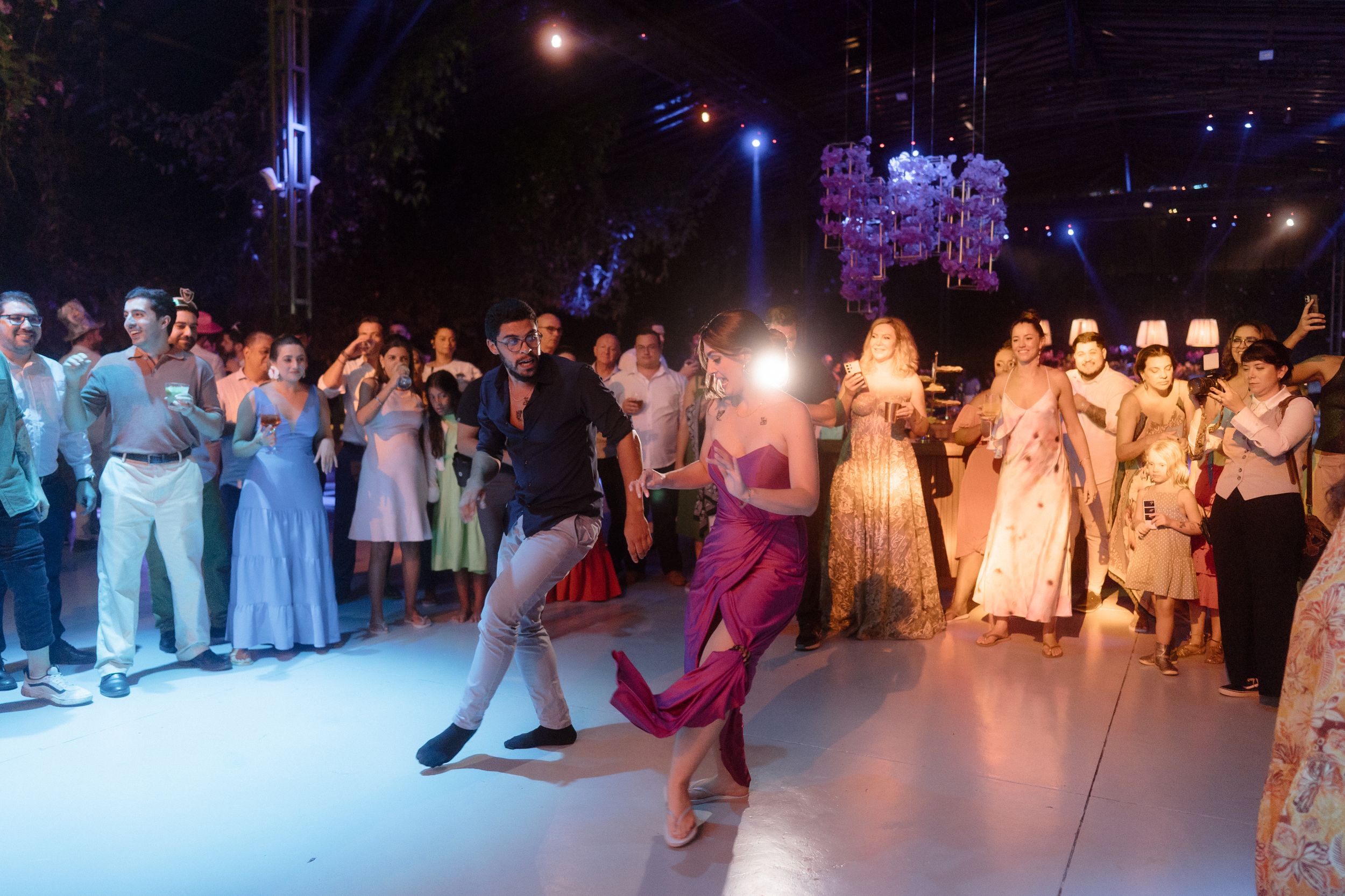 Couples dancing on illuminated dance floor at formal event with crowd watching.