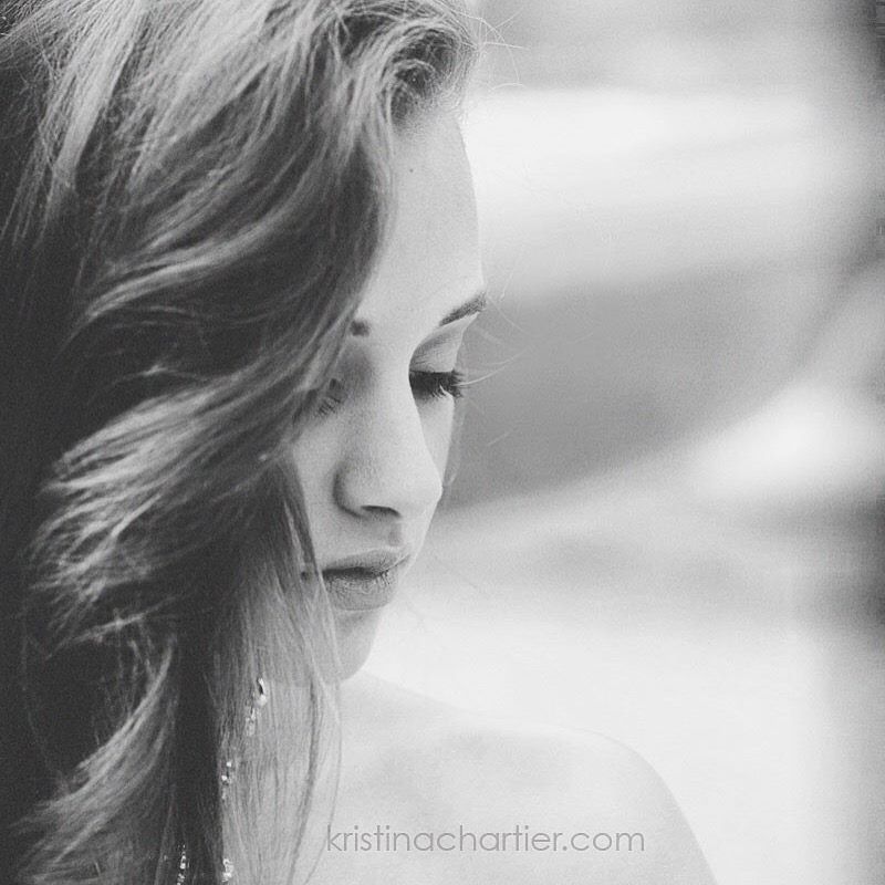 Black and white profile portrait showing wavy hair and a contemplative side view against a soft blurred background.