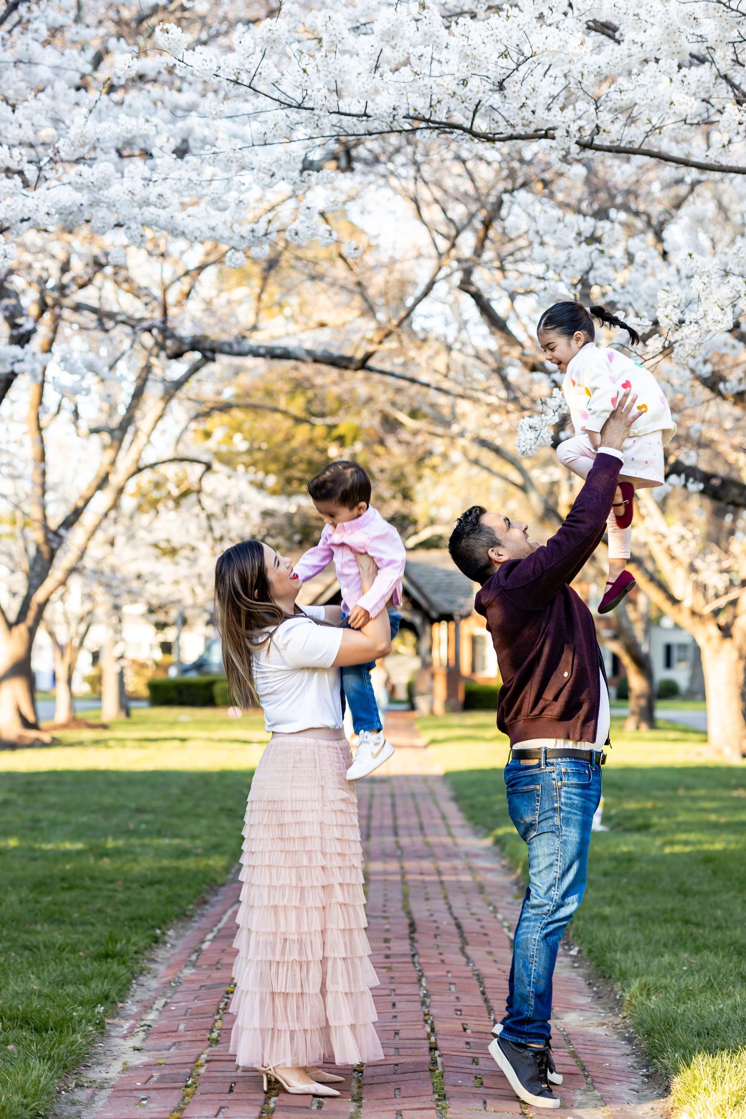 Family enjoying a spring day beneath blooming cherry blossom trees along a brick pathway in a park in Richmond, Virginia