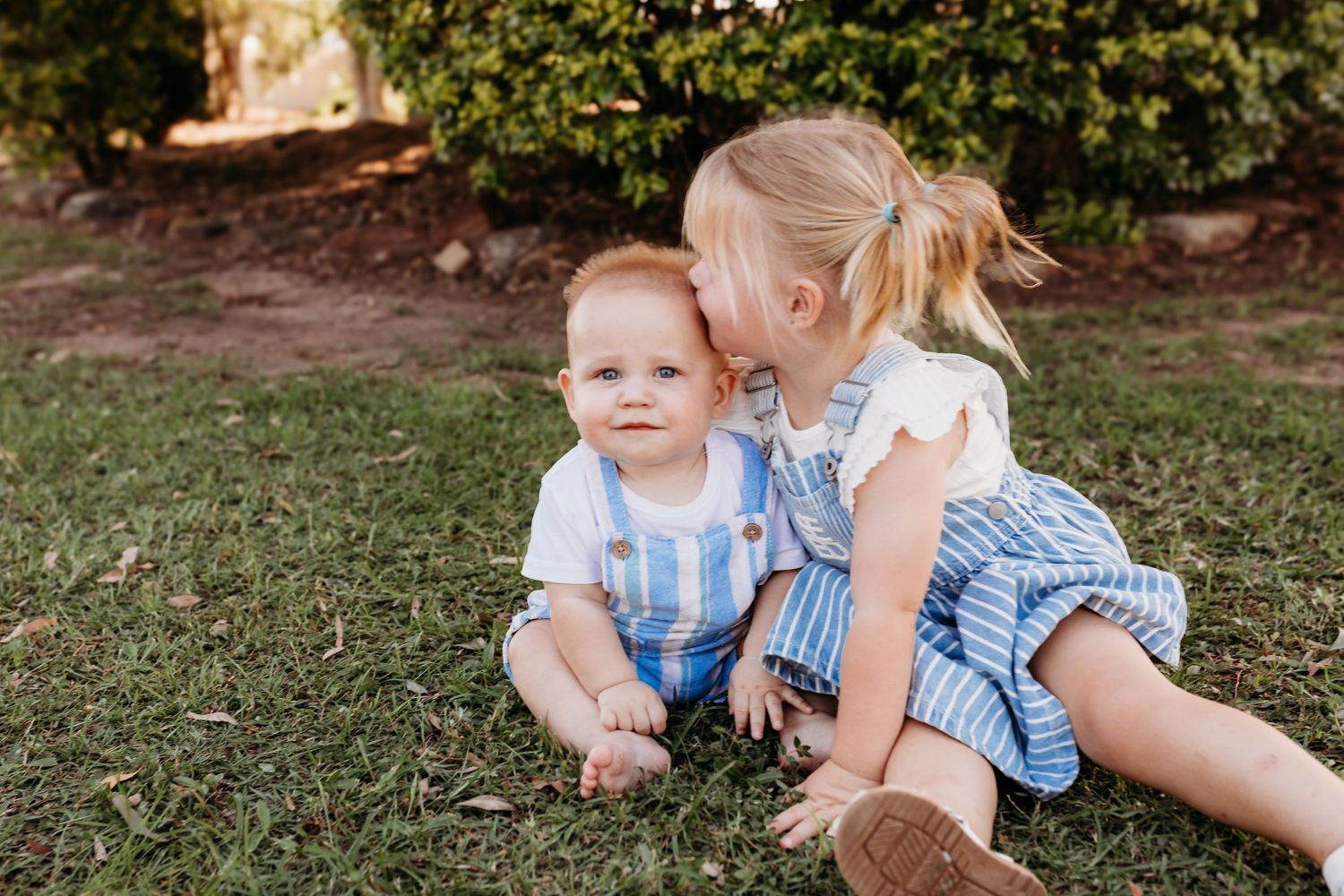 Children playing together on grass in coordinated blue and white outfits.