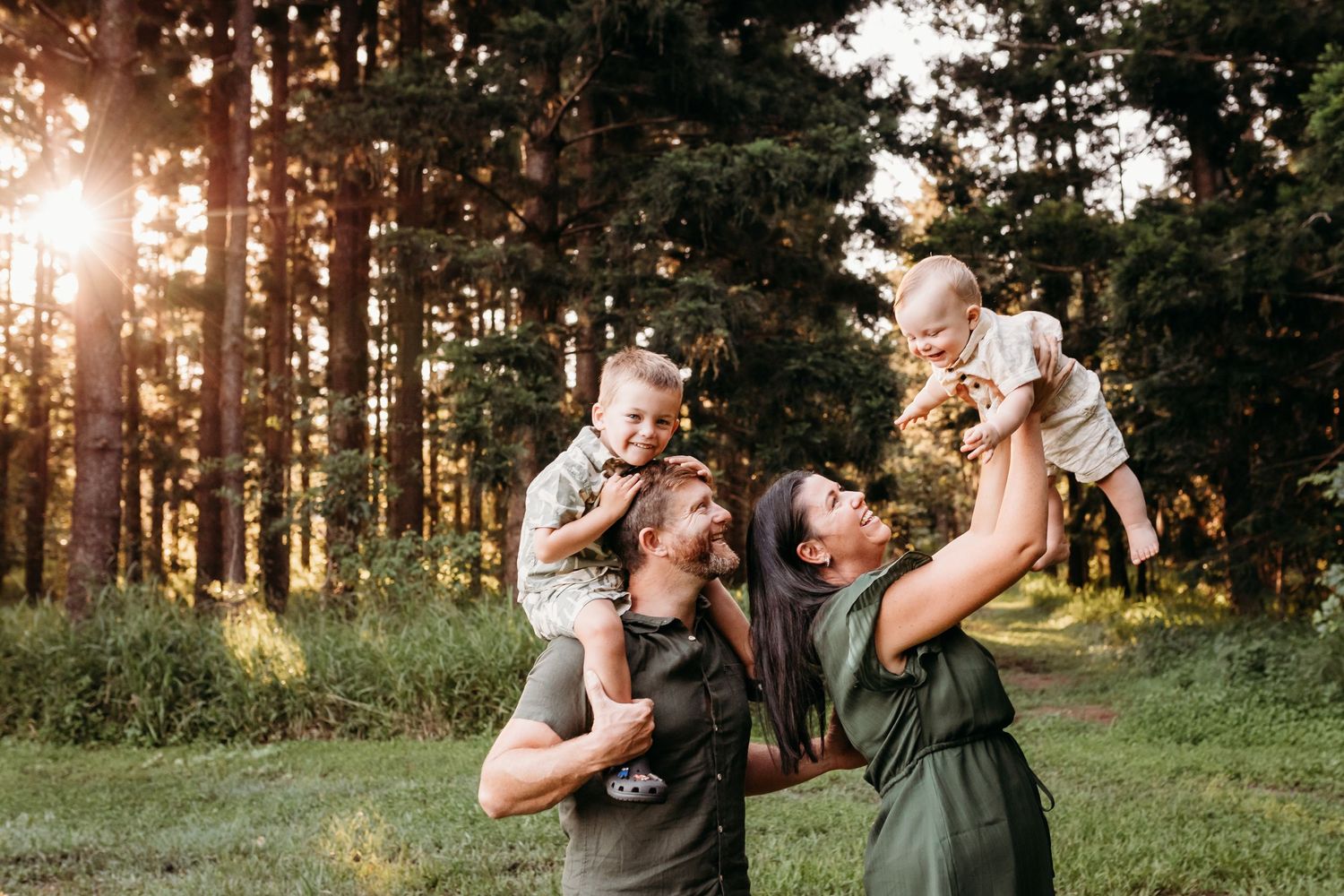 Family sharing joyful moments together in sunlit forest clearing at dusk.