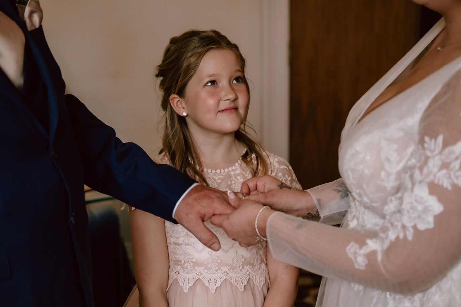 A young attendant in a pink lace dress looks up with a sweet expression during a wedding ceremony at Swindon registry offices