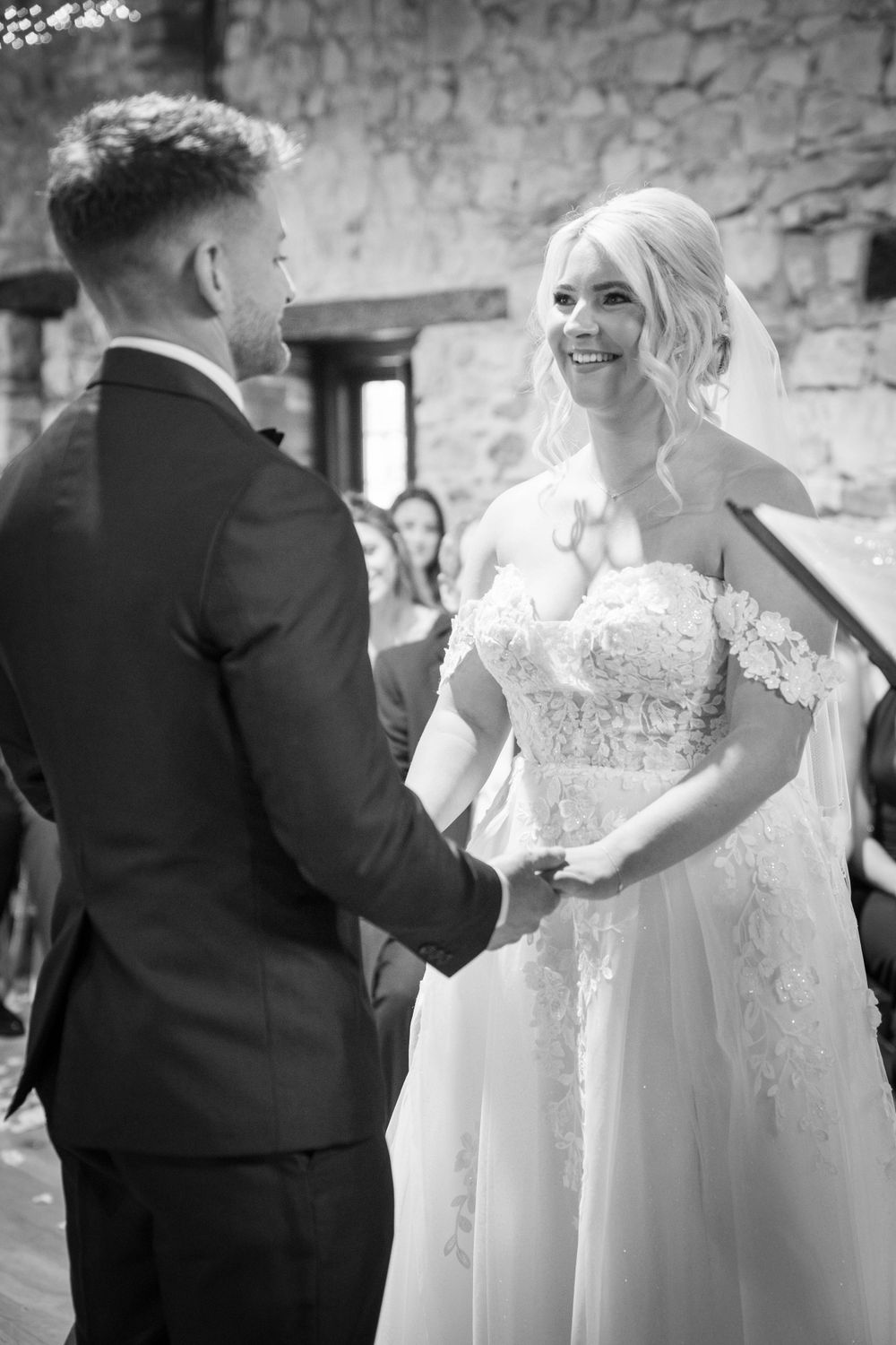 Wedding celebration with people dancing and laughing in a stone-walled venue with string lights.