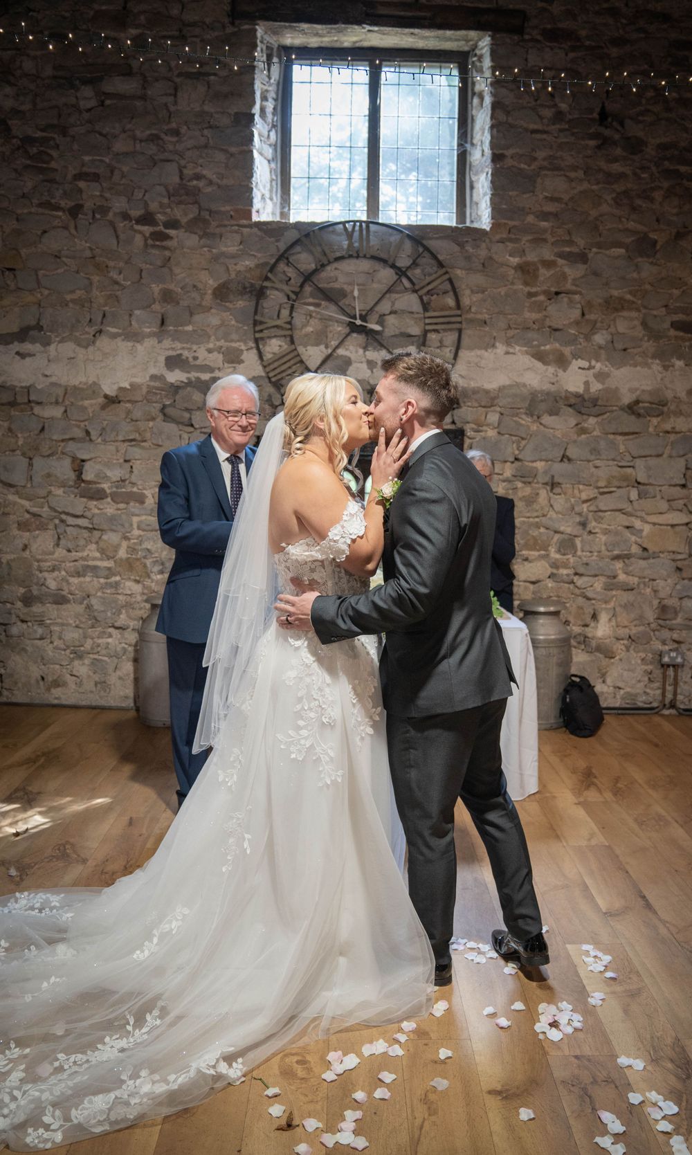 Wedding couple sharing their first dance on a wooden floor in a rustic stone venue.