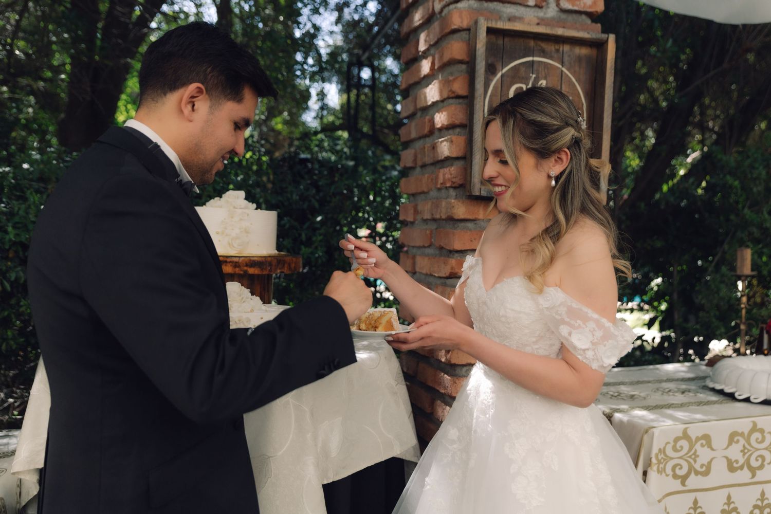 Groom placing ring on brides finger during outdoor wedding ceremony at brick altar.