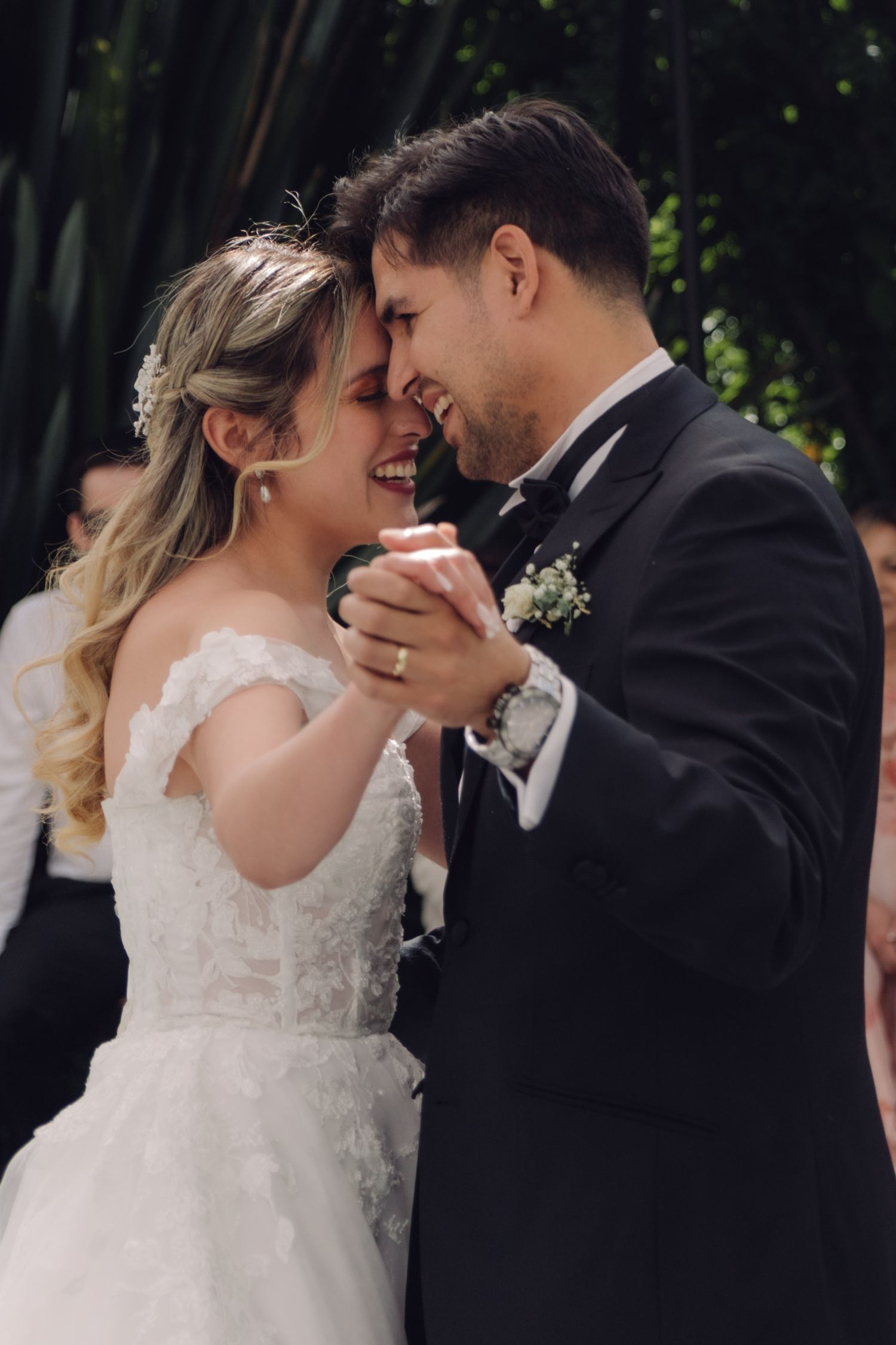 Smiling bride and groom share a joyful intimate moment during their first wedding dance outdoors.