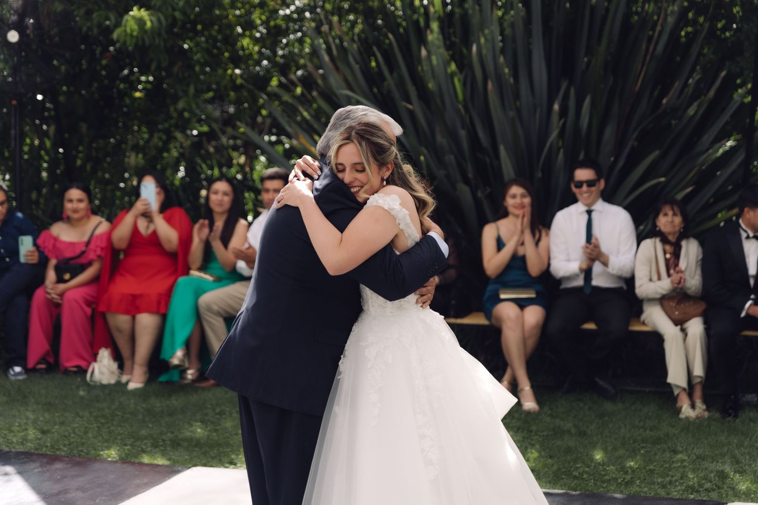 Bride and father share emotional hug during father-daughter dance at outdoor garden wedding.