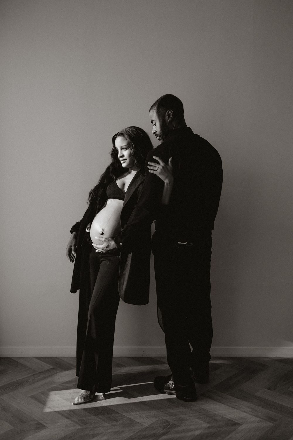 Artistic black and white maternity photo shoot in minimalist setting.