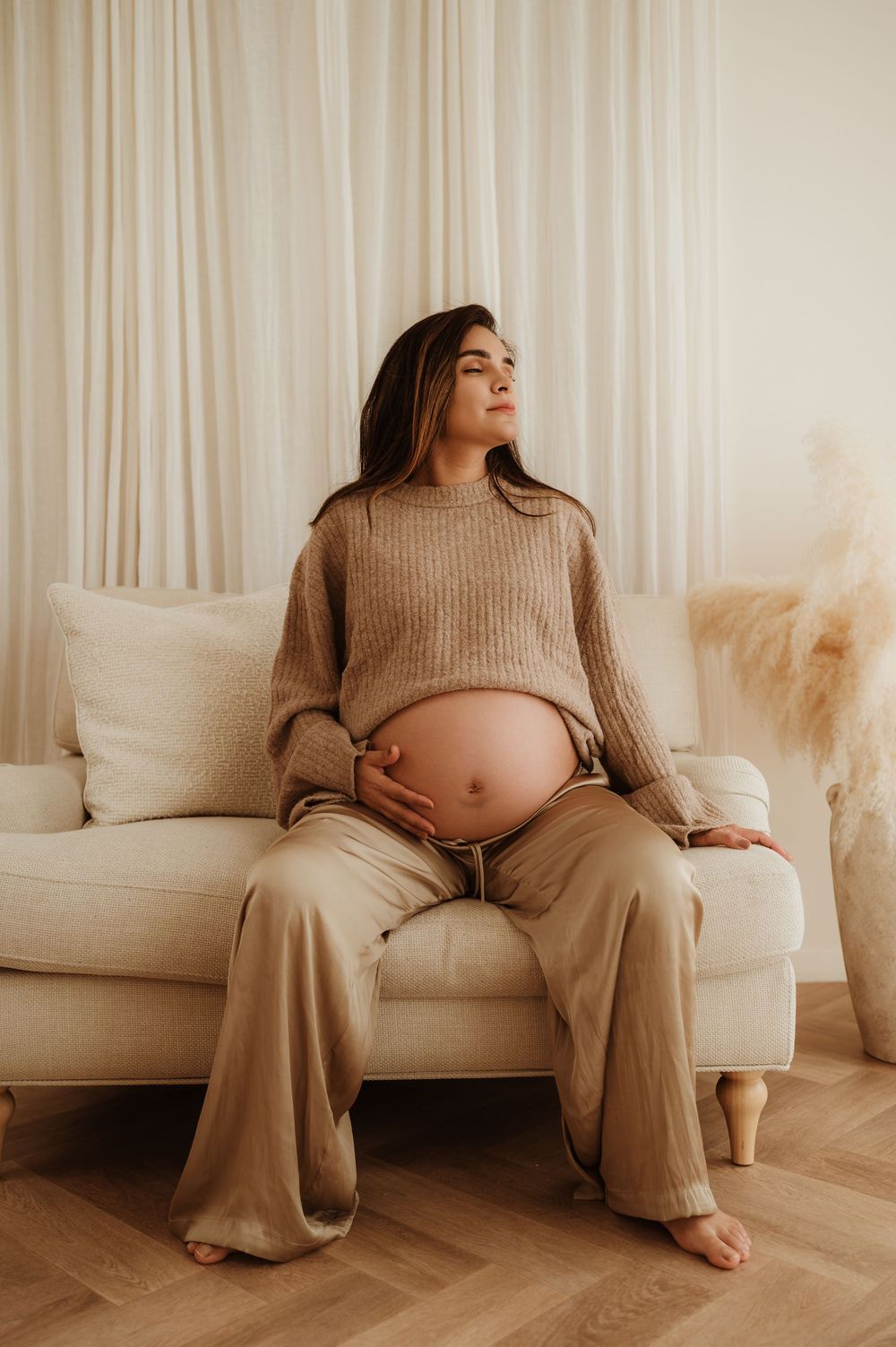 A series of minimalist maternity photos showing a pregnant woman in beige loungewear sitting on a white couch.