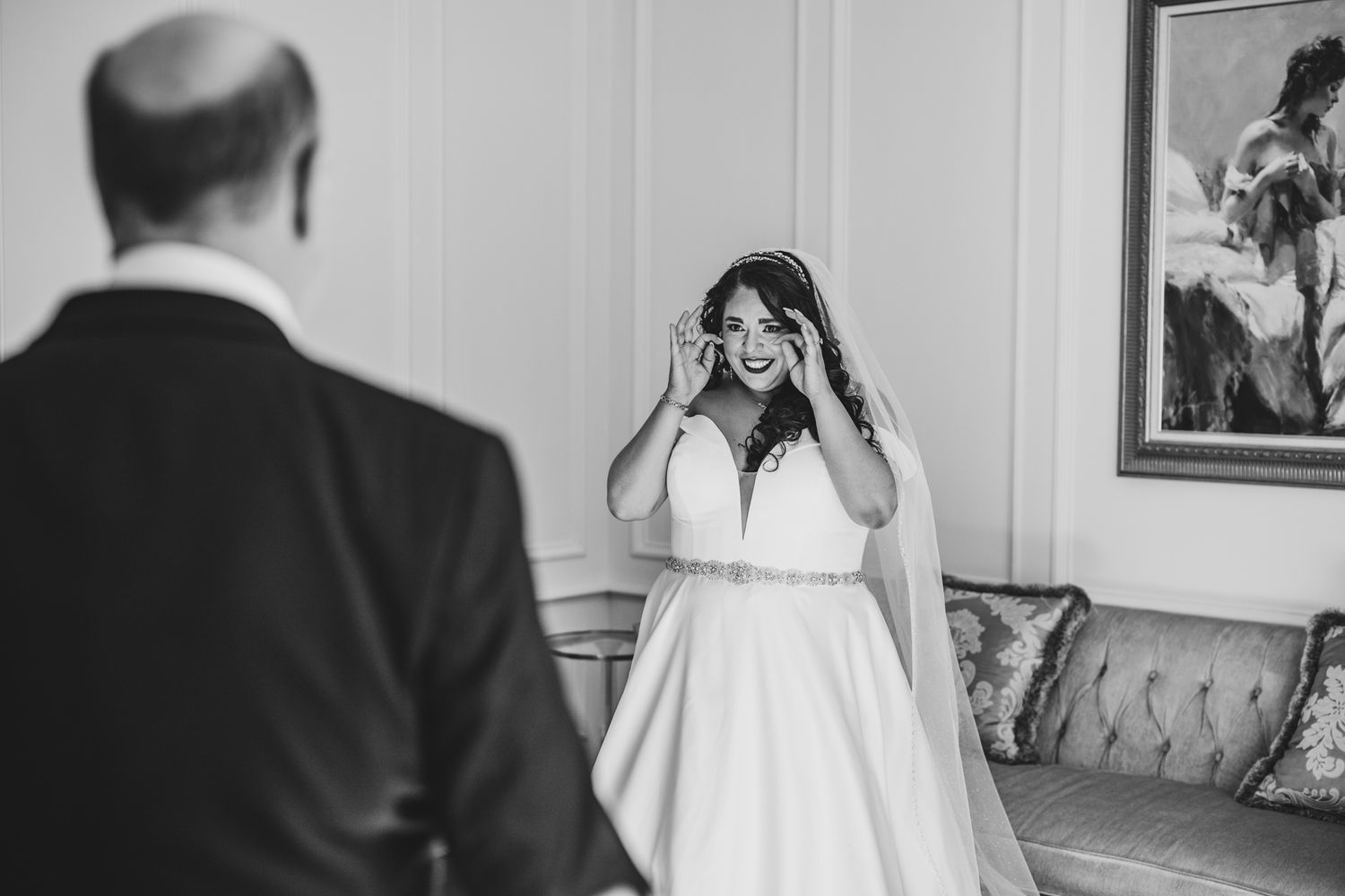 Black and white photo capturing intimate wedding preparation moments in an elegant room.