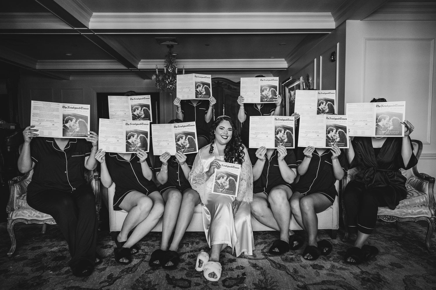 Wedding party holds up fun photo props while posing together on the floor.