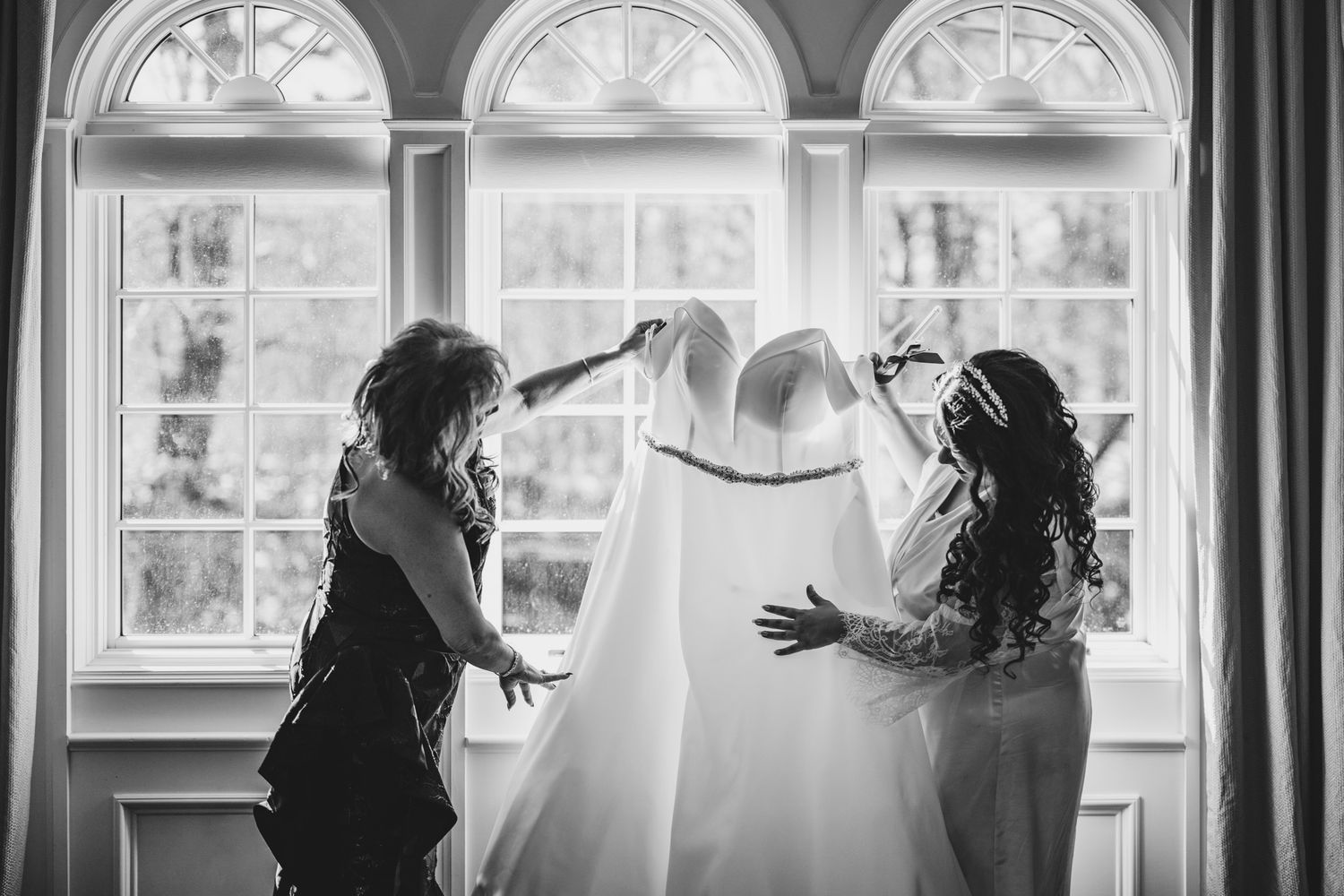 Bridal party celebrates in front of large arched windows in natural light.