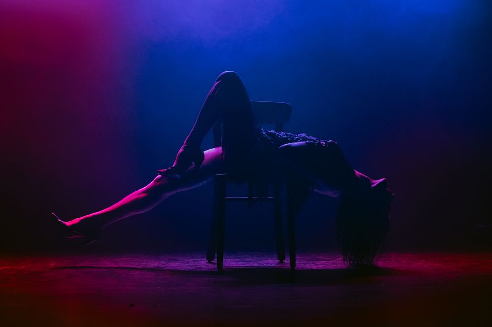 Silhouette of performer on stage in dramatic red and blue lighting.