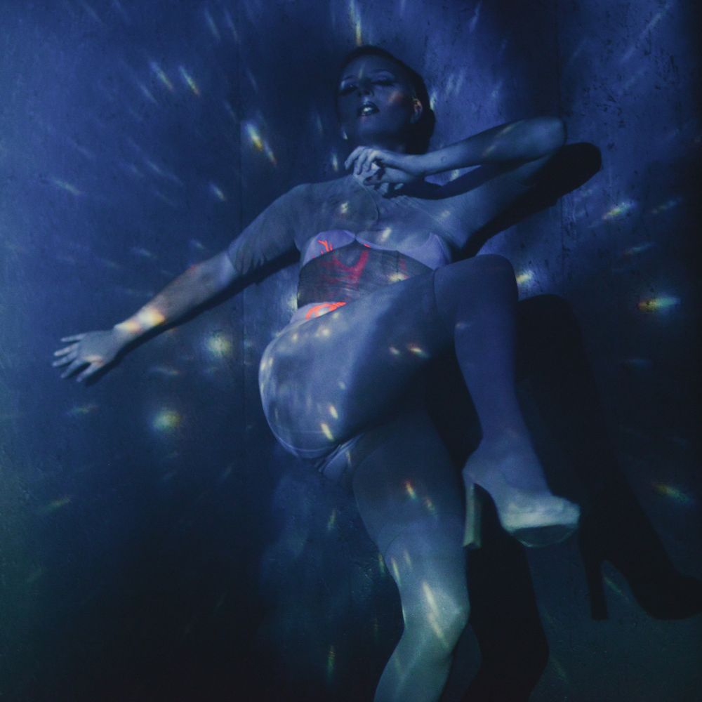 Figure floating underwater in dark blue pool with dramatic lighting effects.
