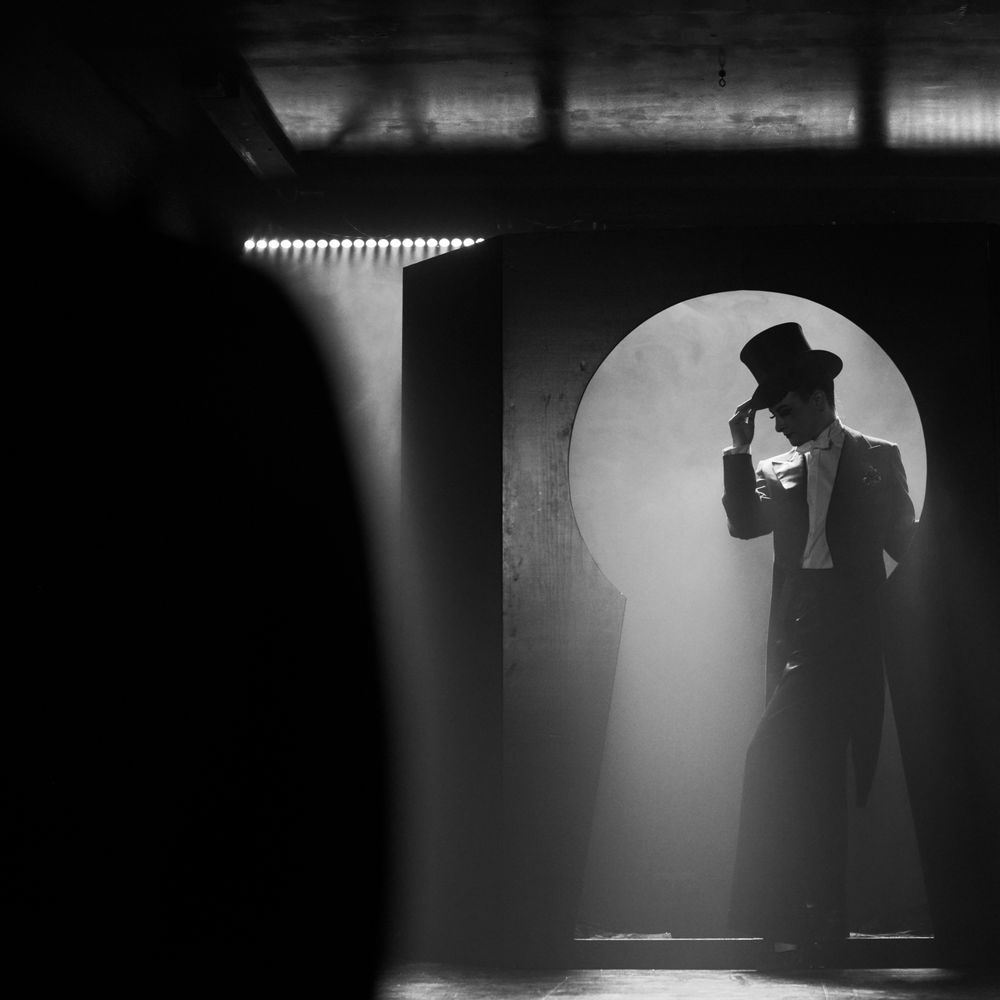 Silhouetted figures in a dimly lit corridor with dramatic backlighting. Cabaret