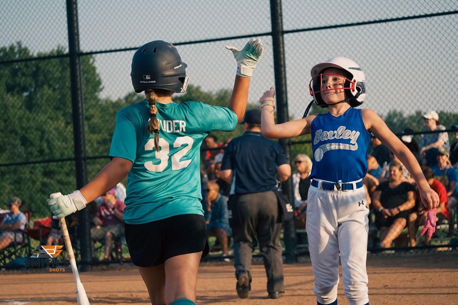 A baseball player runs on a field during a game while teammates can be seen in the background.