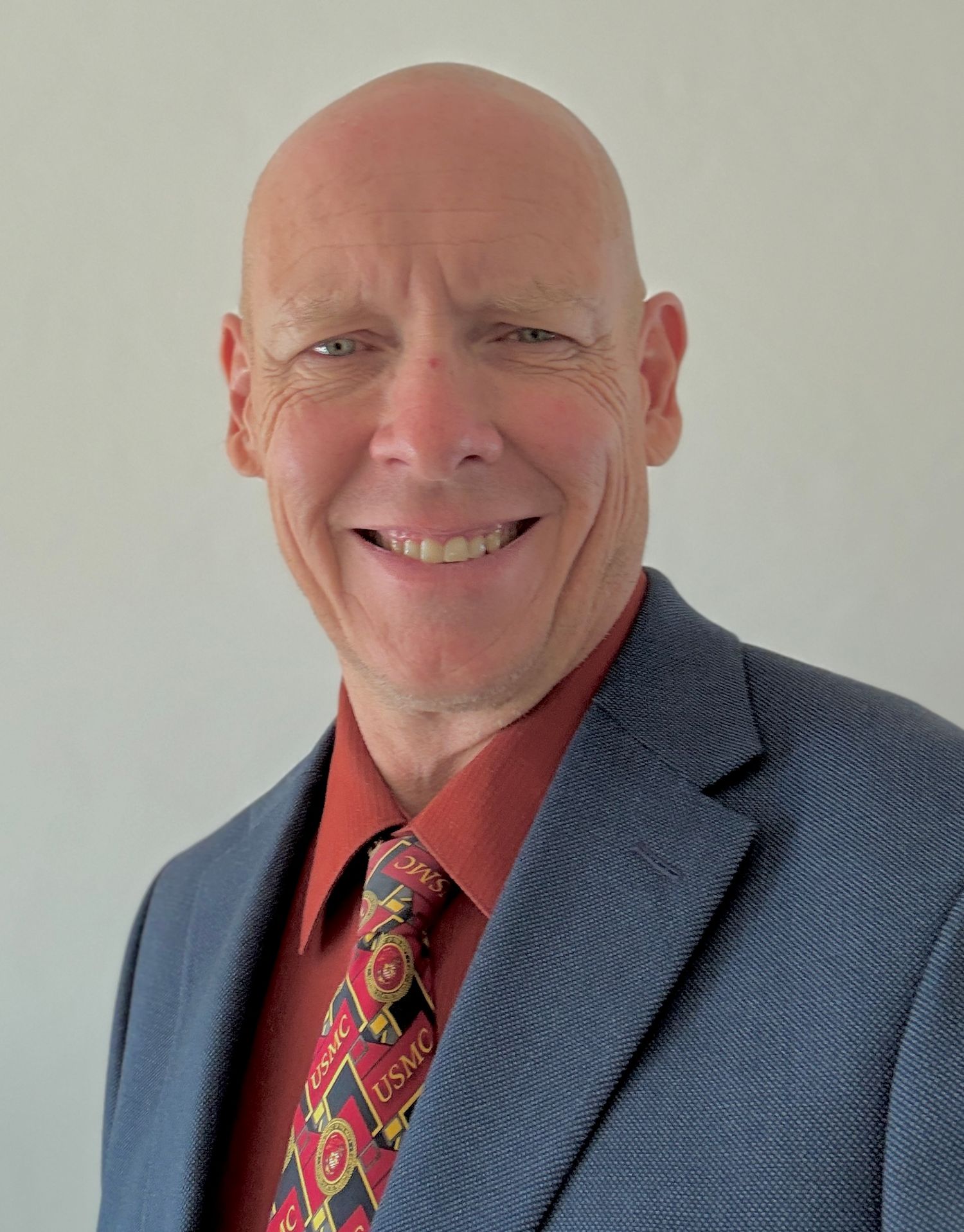 Professional headshot series showing different poses in a blue suit and patterned tie.