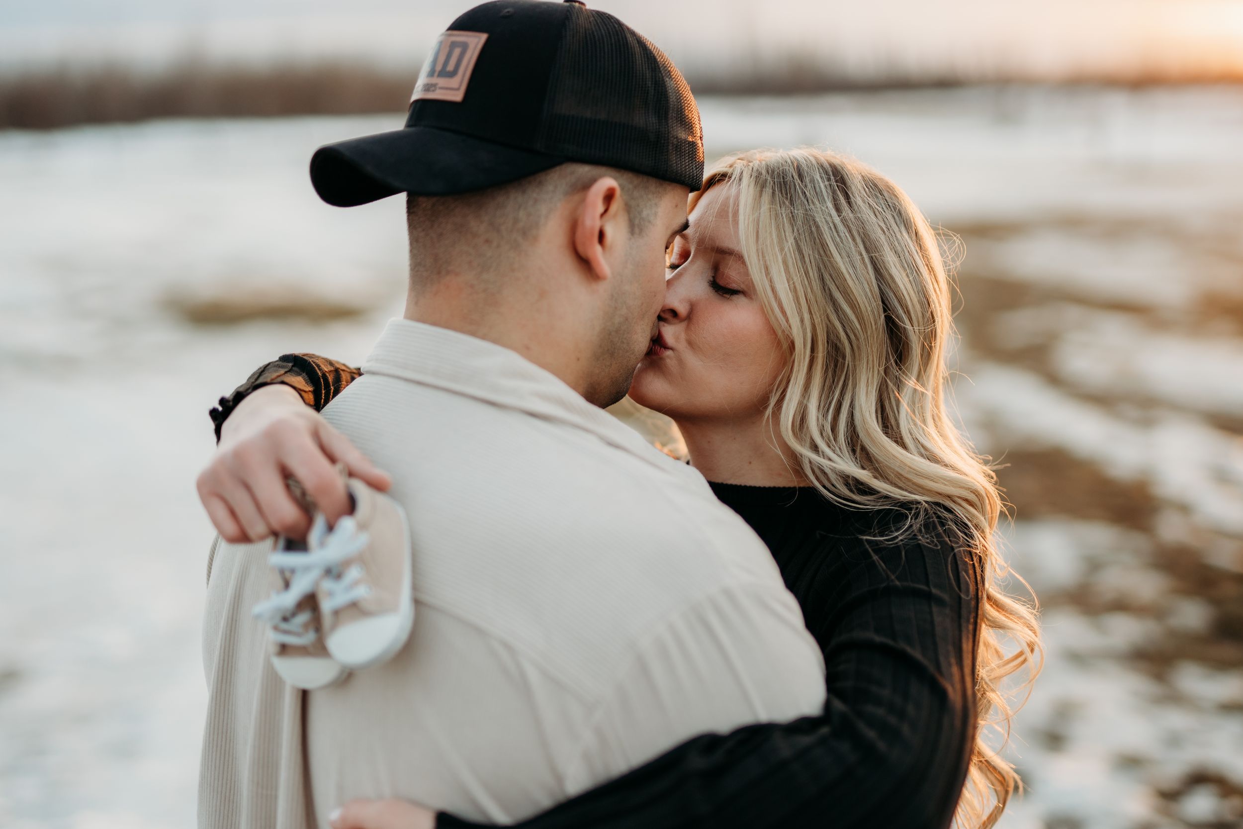 A couple shares an intimate moment at sunset near the water's edge. Fort McMurray photographer