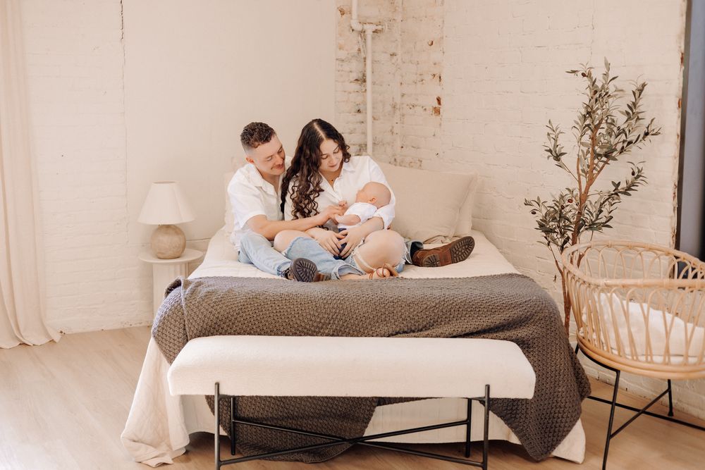 Havelock NC family photographer — parents and children relaxing on a bed in a minimalist home during a lifestyle session.