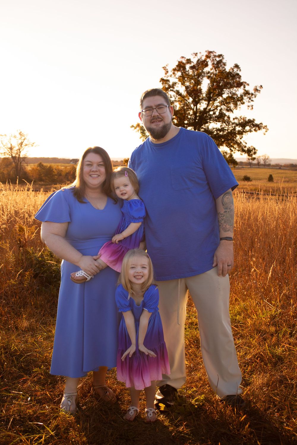 Family photographer in New Bern NC — family posing in a golden field at sunset for a warm, natural portrait.