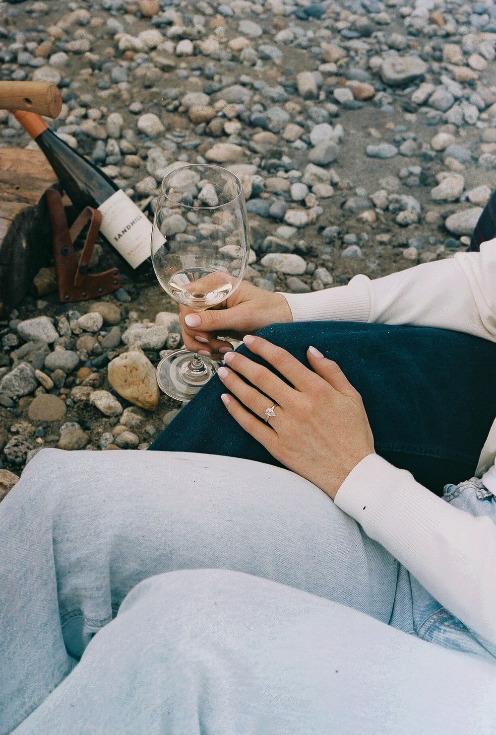 Close-up view of hands holding phones while lying on a blanket by the water.