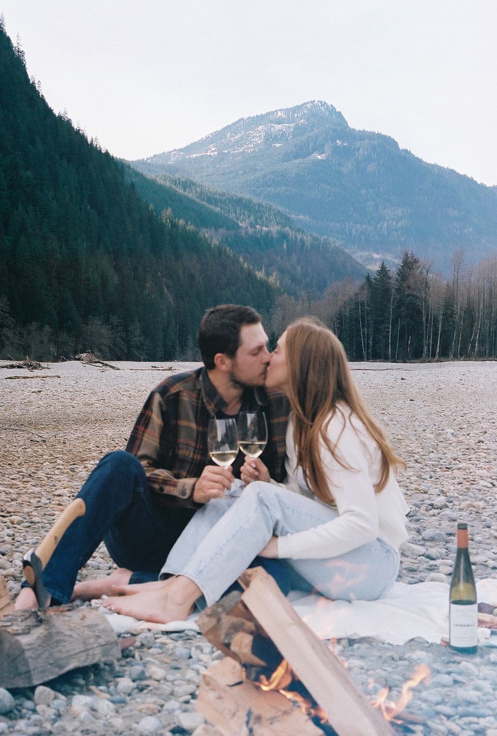 Romantic picnic on rocky beach with mountains and lake in background.