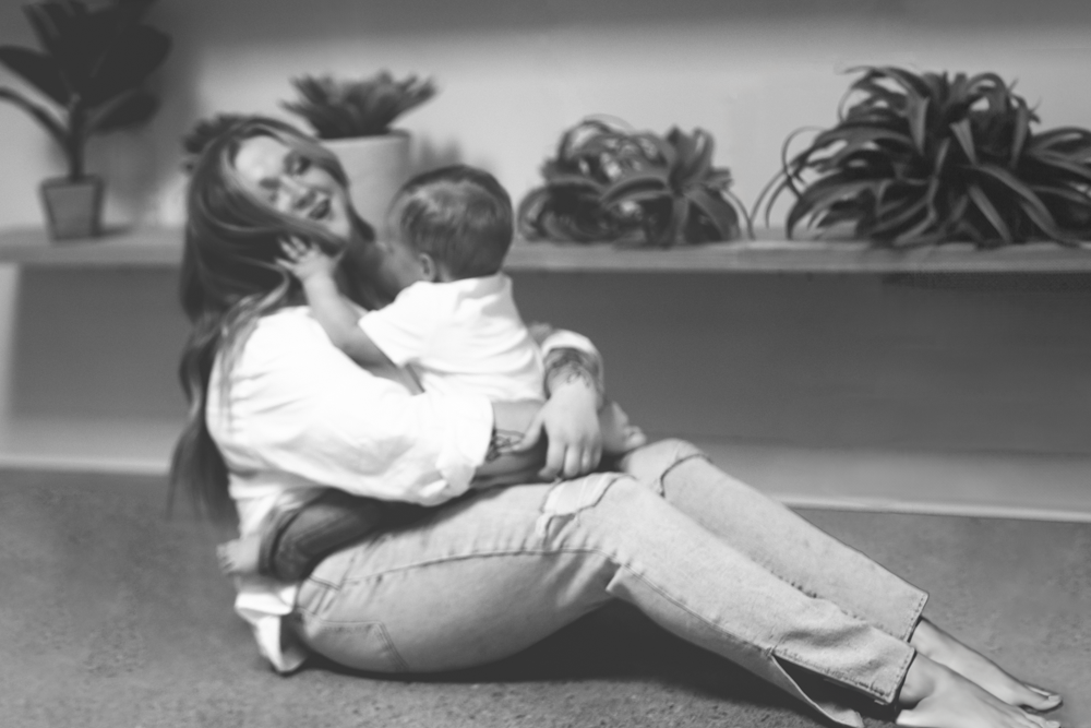 Mother and son playing lovingly on the floor in a black and white photo shoot.