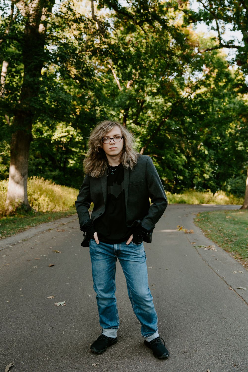 A person in casual wear strikes dynamic poses on an autumn path surrounded by trees.