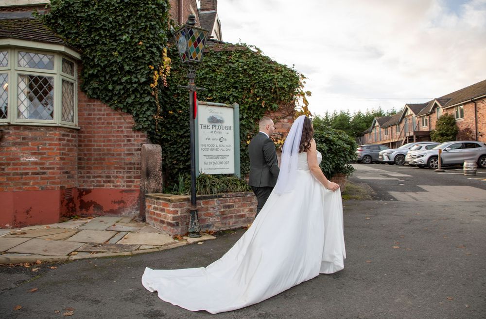 White wedding dress trailing along a rustic brick path with greenery in the background.

The Plough Inn