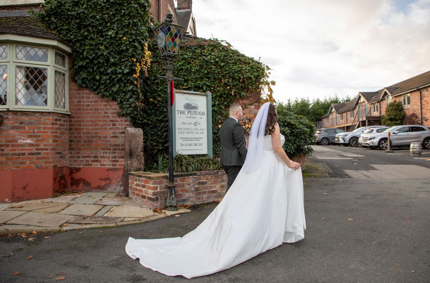 White wedding dress trailing along a rustic brick path with greenery in the background.

The Plough Inn