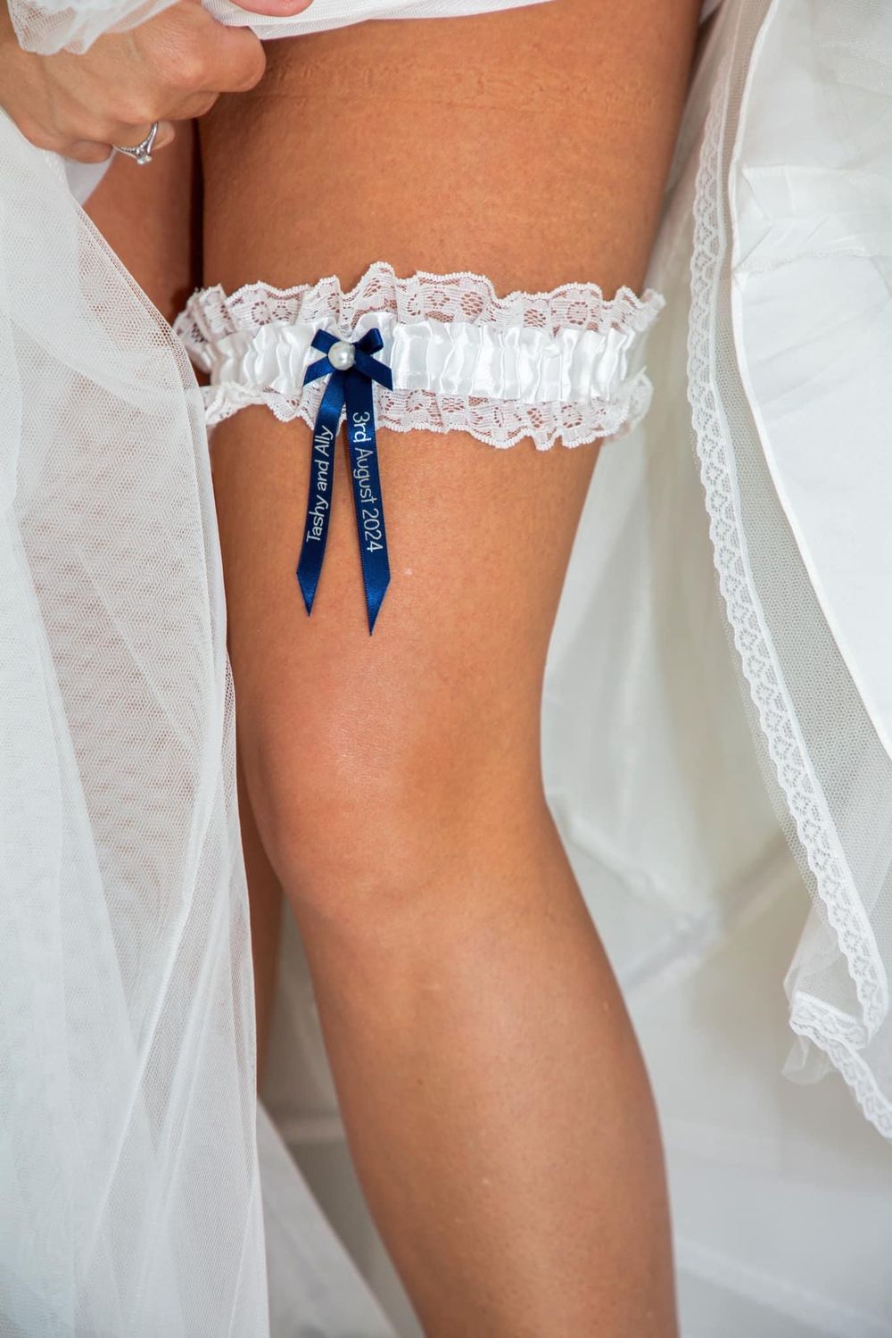 White lace bridal garter with blue ribbon detail on display.
