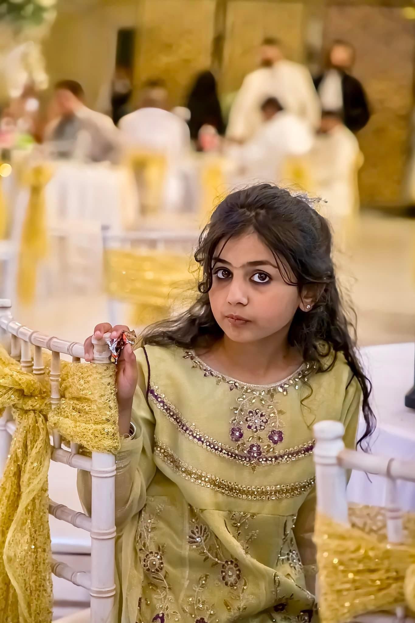 Person in a beige embellished dress seated at an elegant table setting.