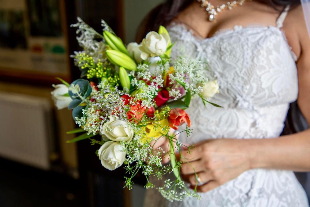 Person in white wedding dress holding colorful floral bouquet.