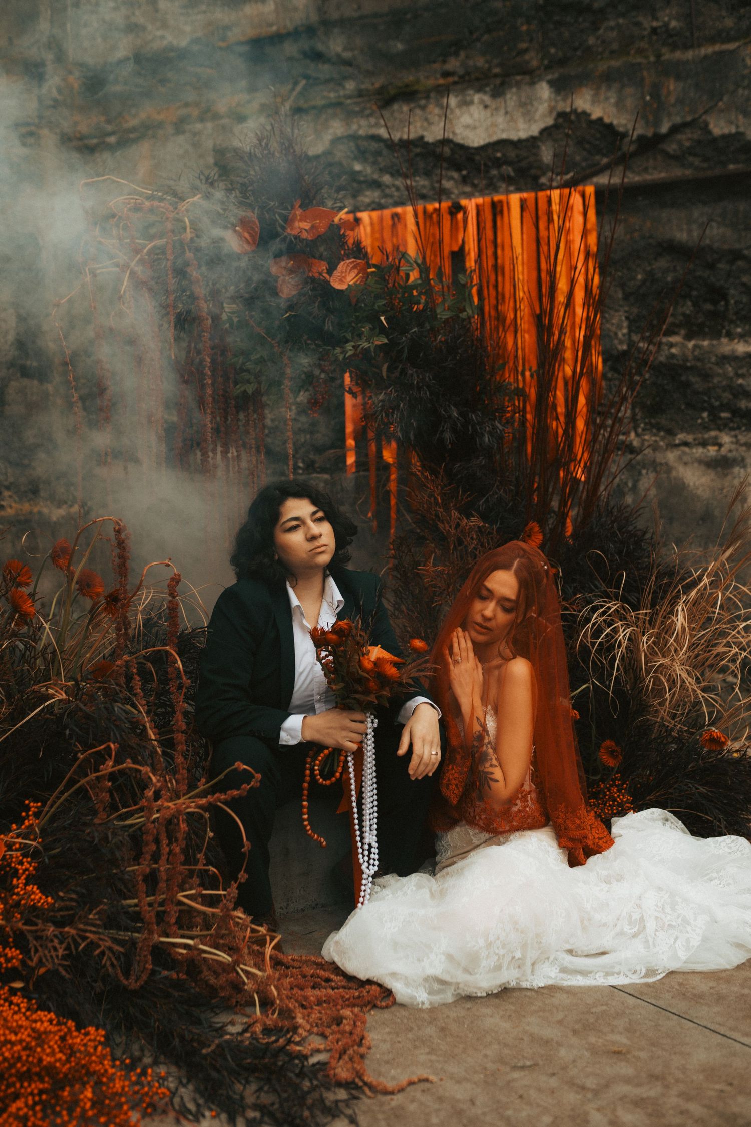 Artistic wedding photo series in dark cave with orange lighting and smoke effects showing couple in dramatic poses.