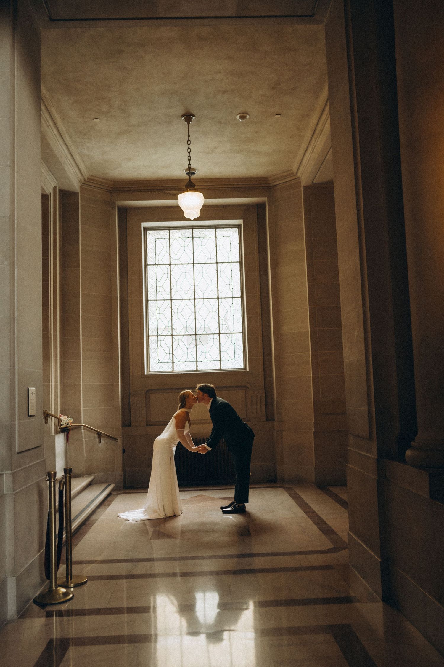 Wedding couple photographed in sequence along a minimalist hallway with natural window lighting.