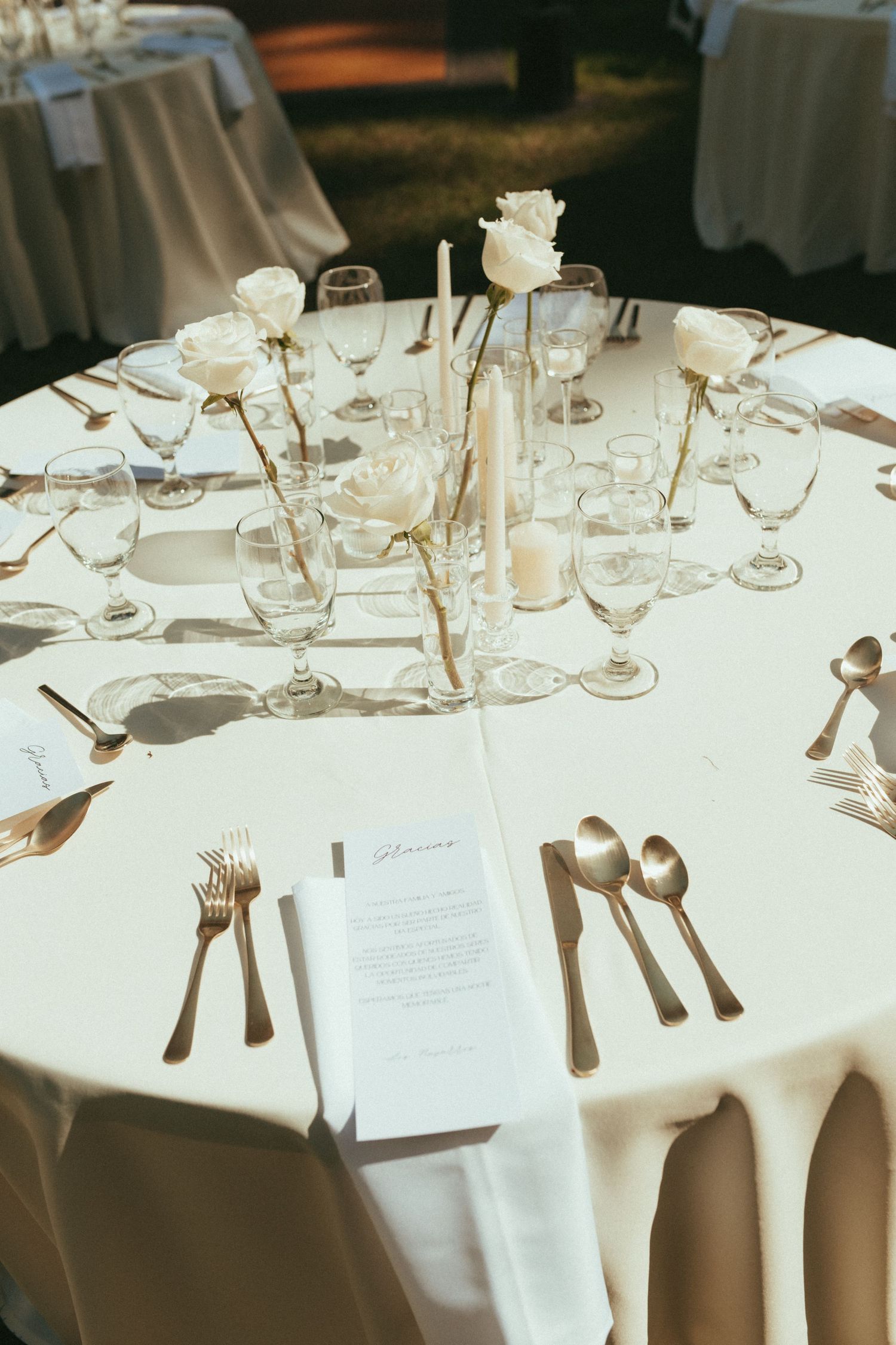 Elegant wedding reception table setting with white linens, formal place settings and delicate floral centerpieces.