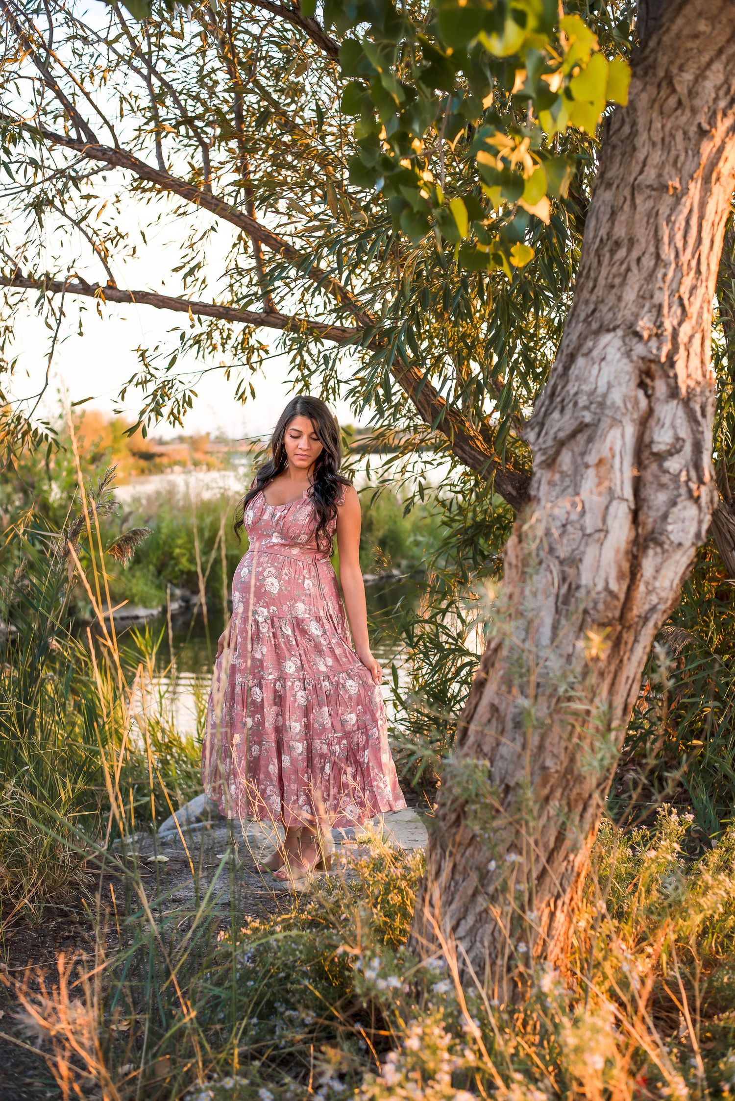 Pregnant mother in a long gown leaning against a tree during a fall maternity session in Bountiful, Utah