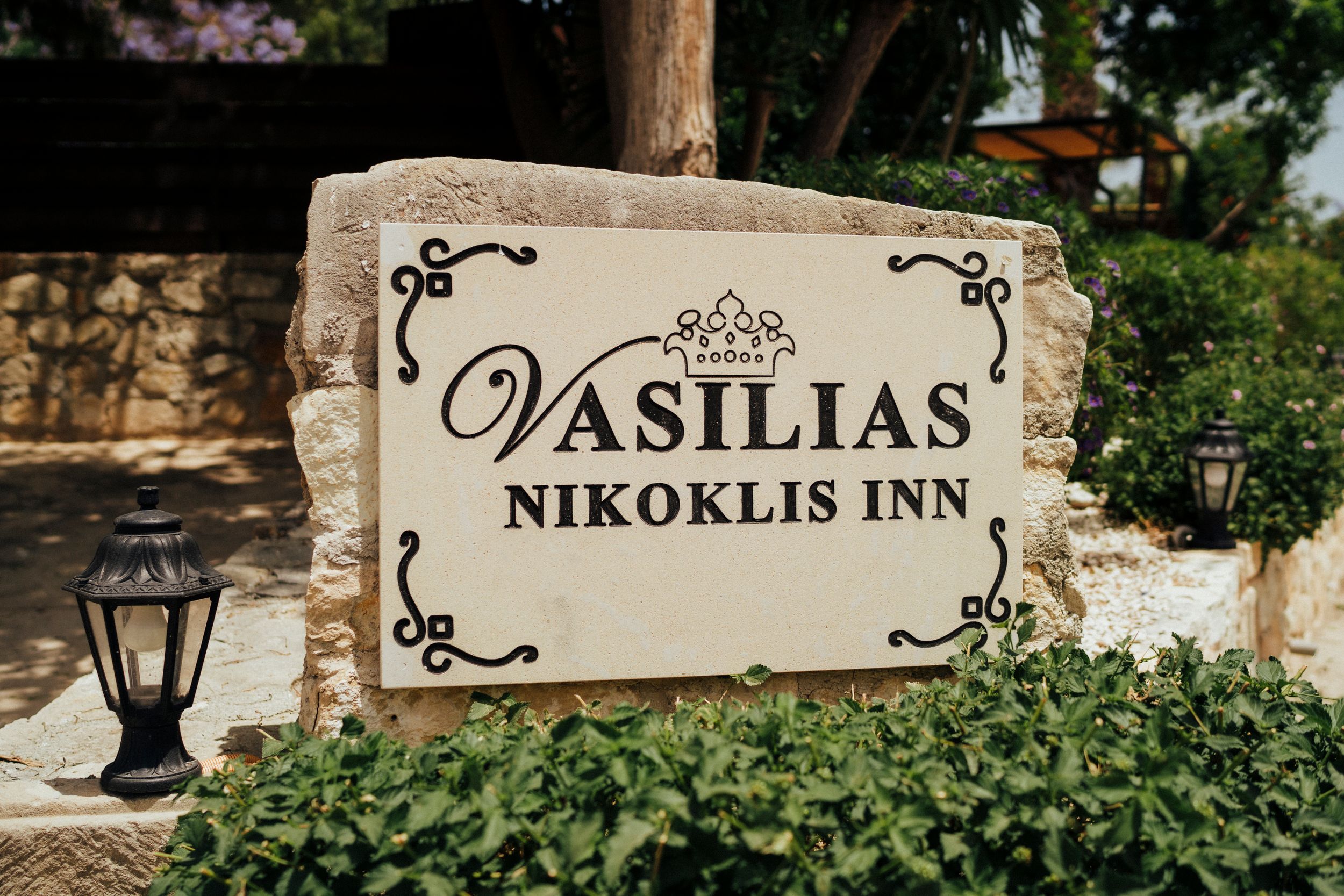 Stone sign for Vasilias Nikoklis Inn with decorative flourishes and lantern.