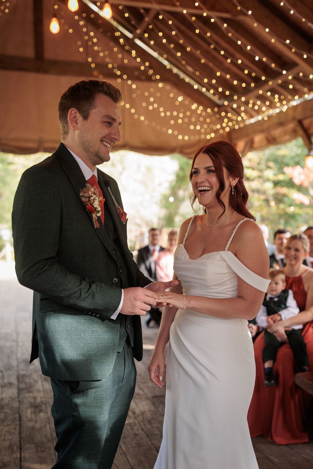 A couple shares a joyful moment during their first dance at a wedding reception under twinkling string lights.