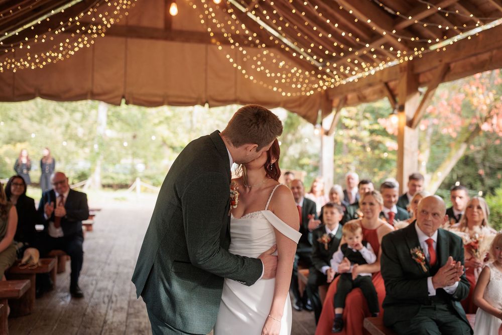 A romantic wedding dance under a tent decorated with twinkling string lights as guests watch from their seats.
