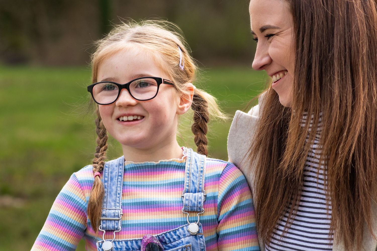 Mum and 6 year old daughter sharing a giggle during an Autumn photoshoot in Ashtead woods.